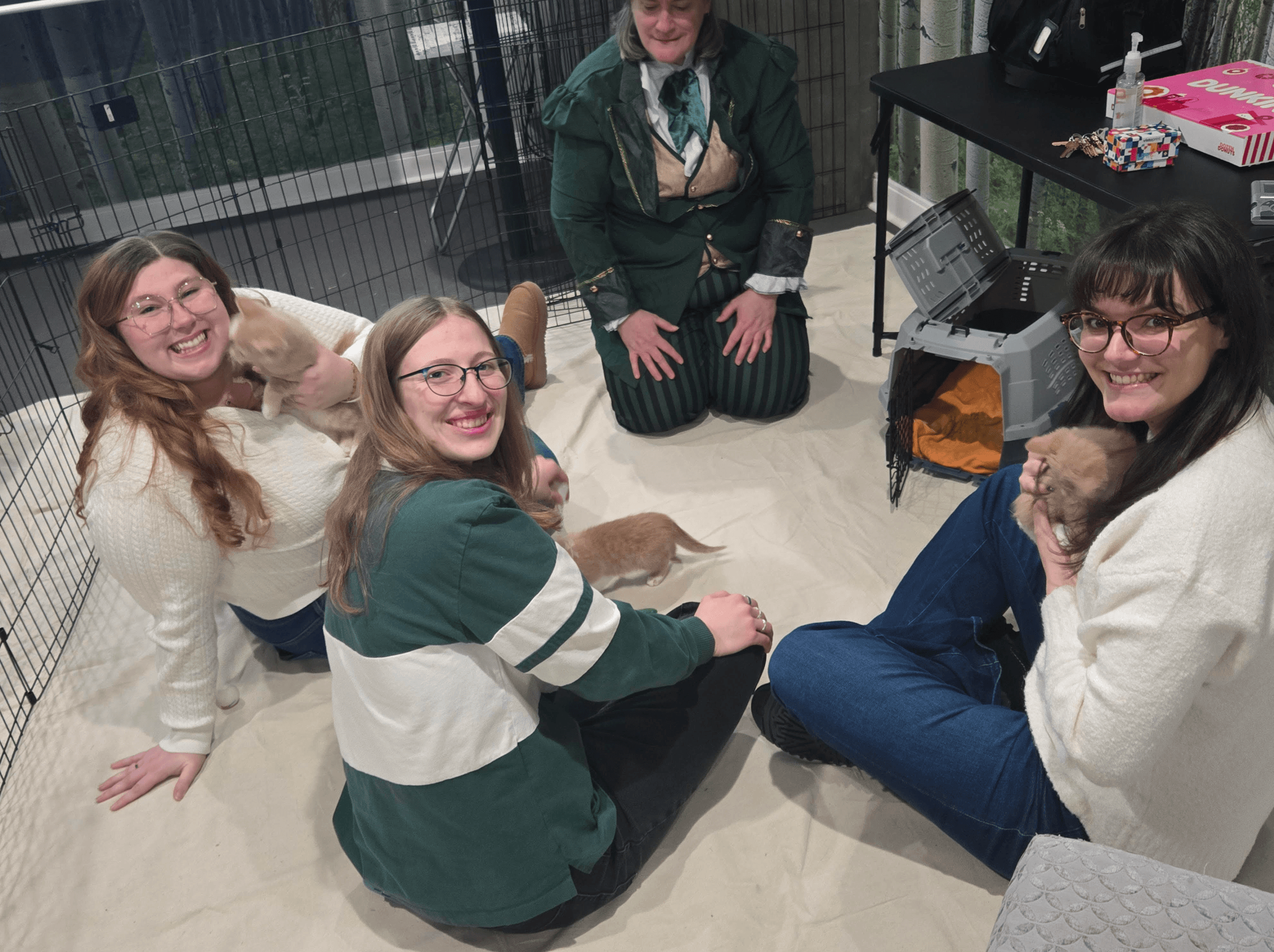 People sitting on the floor of a room petting cats