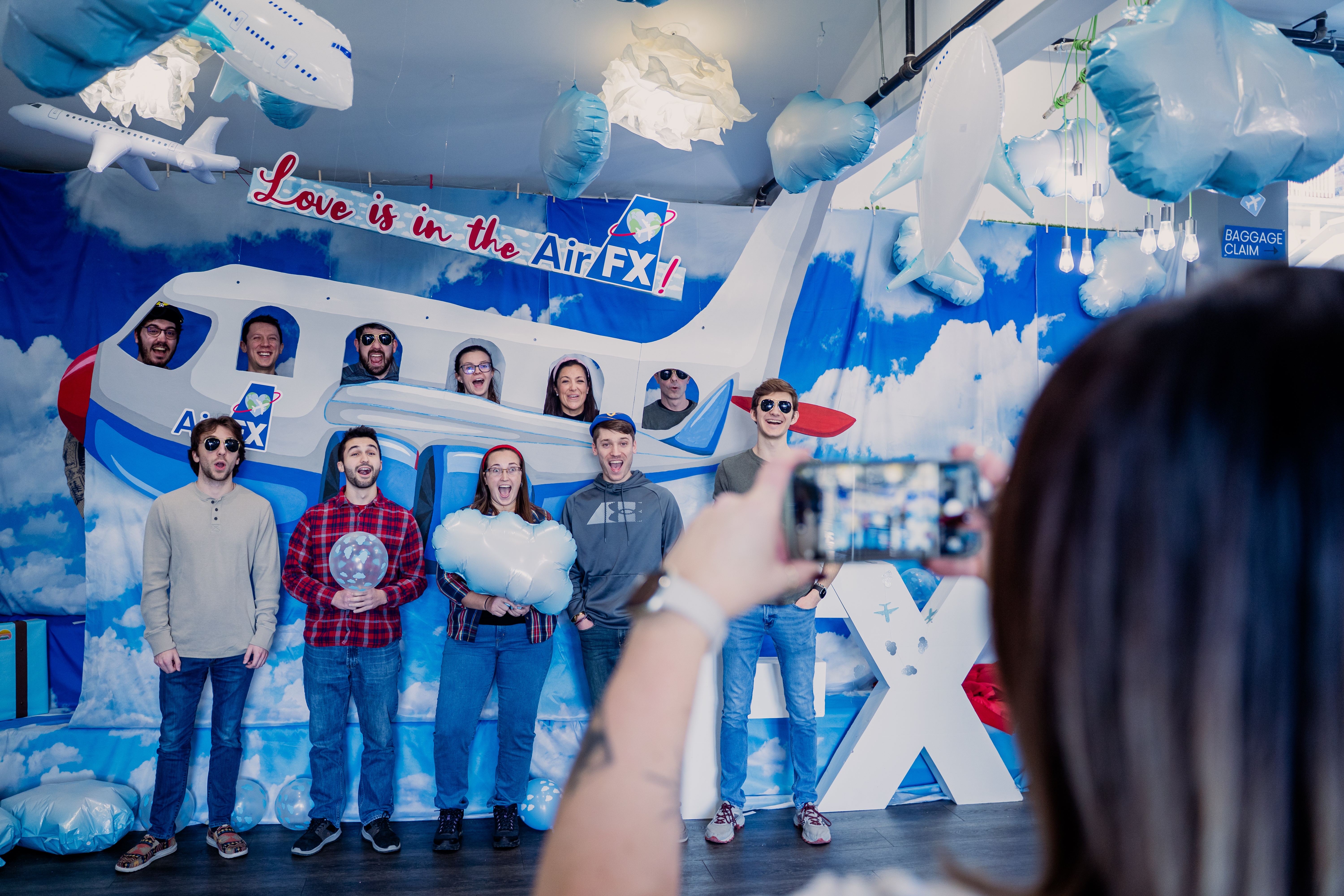 Group of people standing in front of a cardboard plane, posing for a picture