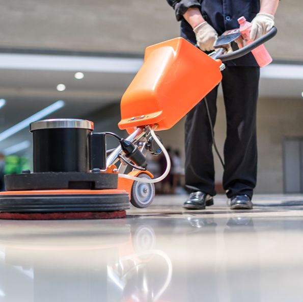 Worker in white gloves operating an orange floor buffer